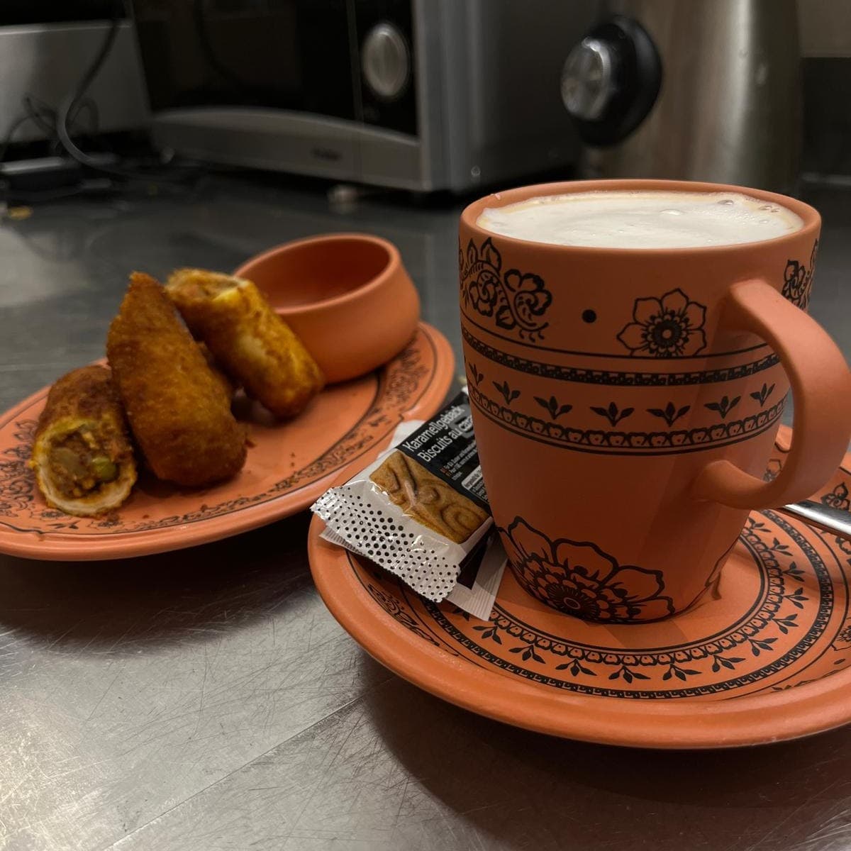 Chai in Terracotta-Tasse mit frittierten tamilischen Snacks
